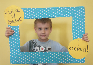 Chłopiec w szarej koszulce pozuje w ramce