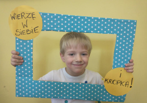 Chłopiec w białej koszulce pozuje w ramce