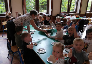 Dzieci na jadalni przy wspólnym stole czekają na degustację sałatki
