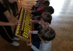 Dzieci oglądają i przesuwają koraliki na japońskim liczydle