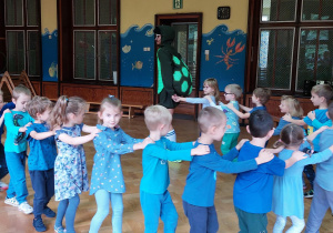 dzieci ubrane w niebieskie koszulki tańczą w wężyku