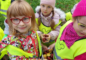 trzy dziewczynki prezentują torbę pełną kasztanów