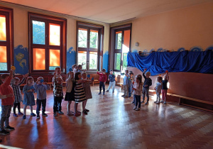 Na zdjęciu dzieci ustawione w pociąg trzymają kolorowe uśmiechnięte buźki