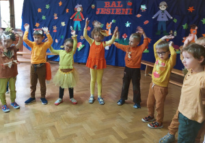 Zdjęcie grupowe – dzieci w jesiennych strojach stoją na tle jesiennej dekoracji