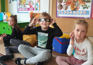 Na zdjęciu chłopiec przymierzający specjalne okulary do oglądania zjawiska zaćmienia słońca.