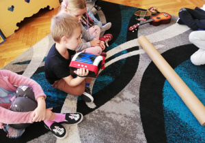Na zdjęciu chłopiec próbuje grać na malutkim akordeonie
