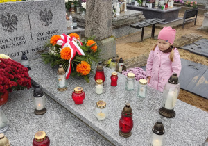 Dziewczynka zapala znicz przy grobie Nieznanego Żołnierza.