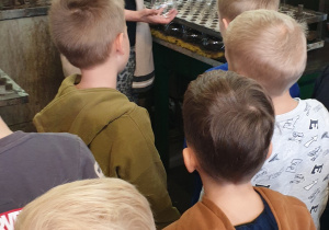 Na zdjęciu dzieci słuchają pani opowiadającej o procesie powstawania bombek.