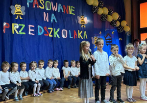starszaki podczas recytacji wierszy na tle dzieci z grupy pierwszej