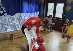 dziecko wraz z nauczycielką ubiera Mikołaja z papieru