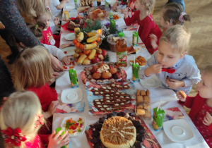 Dzieci siedzący przy stole zastawionym smakołykami