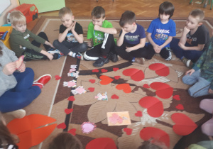 na zdjęciu dzieci wraz z nauczycielką przeliczające i segregujące emblematy walentynkowe