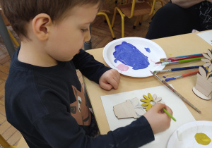chłopiec malujący drewnianego kwiatka