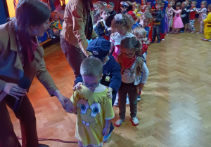 Na zdjęciu dzieci ustawione w pociąg przeskakują po kolei przez linę.