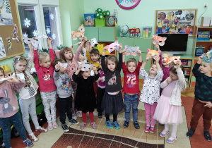 Zdjęcie grupowe dzieci trzymających wysoko maski kota.