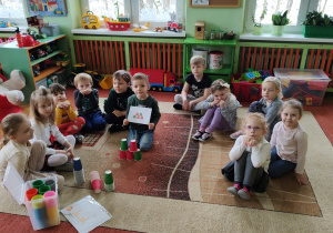 dzieci siedzące na dywanie podczas zadania polegającego na odwzorowaniu układu kubeczkowego.
