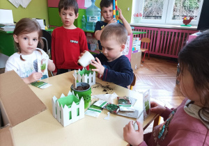 Na zdjęciu dzieci wsypują nasiona do doniczki