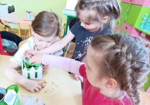 Na zdjęciu dziewczynki sieją owies w doniczkach
