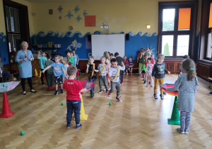 Dzieci stojące w trzech rzędach. Konkurencja sportowa ze szczotkami i biedronkami.