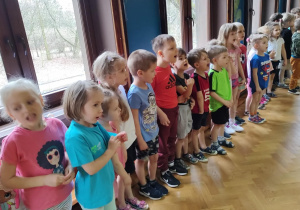 Dzieci stojące w półkolu na sali gimnastycznej.