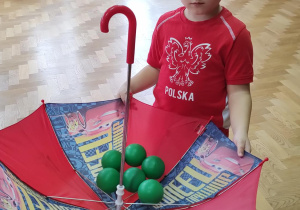 Chłopiec trzymający odwróconą parasolkę z piłeczkami.