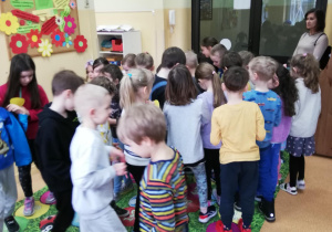 dzieci chodzą po kolorowej macie przy dźwiękach muzyki