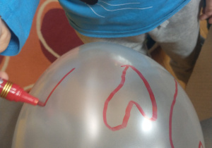 Chłopiec maluje balon.