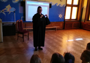 Pani adwokat w todze pokazuje zielony żabot adwokacki