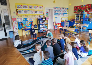 dzieci w klasie inscenizują rozprawę sądową - po środku siedzi sędzia, po bokach adwokaci z klientami, przygląda im się grupa dzieci - widownia