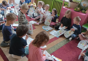 Na zdjęciu dzieci oglądające otrzymane upominki