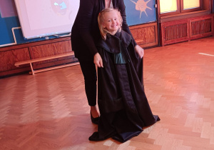 Na zdjęciu dziewczynka przymierza togę adwokacką.