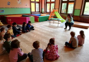 dzieci siedzą w półkolu, prowadząca nadmuchuje balon zamknięty w plastikowej butelce