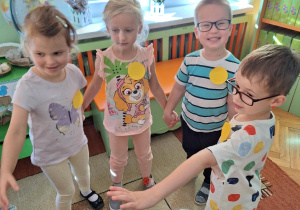 Dzieci biorą udział w zabawach ruchowych, mają przyklejone do ubrań kolorowe kropki.