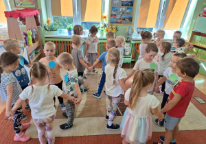 Dzieci biorą udział w zabawach ruchowych, mają przyklejone do ubrań kolorowe kropki.