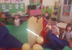 zdjęcie przedstawia dzieci z grupy ,,Misie” podczas zabawy z chustą animacyjną i balonami