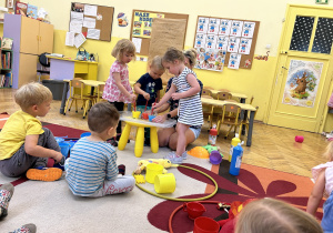 na zdjęciu dzieci uczestniczą w eksperymencie mieszania kolorowych płynów.
