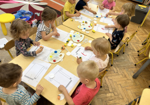 Na zdjęciu dzieci wykonują prace plastyczne z użyciem akcesoriów kosmetycznych.