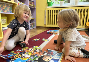 Na zdjęciu dwie dziewczynki układają puzzle na dywanie.