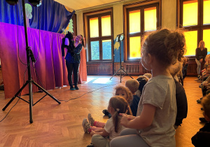 Na zdjęciu aktorka teatrzyku z pacynką kotka oraz obserwujące ją dzieci.