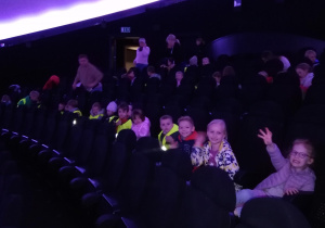 dzieci siedzą na wygodnych fotelach na sali w Planetarium