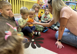 Na zdjęciu dzieci wąchają przekrojoną wcześniej dynię.