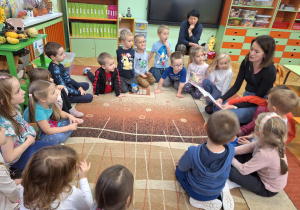 Na zdjęciu mama Tadzia czyta dzieciom bajkę.