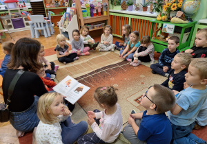 Na zdjęciu mama Tadzia czyta dzieciom bajkę.