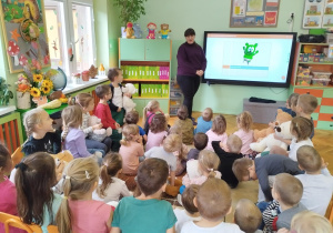 dzieci siedzące przed tablicą mutimedialną
