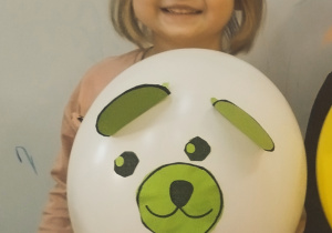 dziewczynka prezentująca misia wykonanego z balinika