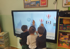 dzeci podczas wykonywania zadania z wykorzystaniem tablicy multimedialnej