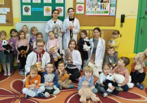 Wspólne zdjęcie grupowe dzieci trzymających swoje misie z zaproszonymi studentami
