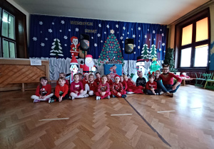 grupa dzieci w strojach mikołajkowych na tle dekoracji zimowo-świątecznej