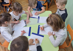 Na zdjęciu dzieci siedzą przy stolikach, projektują wnętrze swoich pokoi.