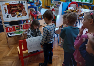 dzieci kupują w kasie zrobionej z ławeczki na niby bilety do teatrzyku " Bajkowa kawiarenka"